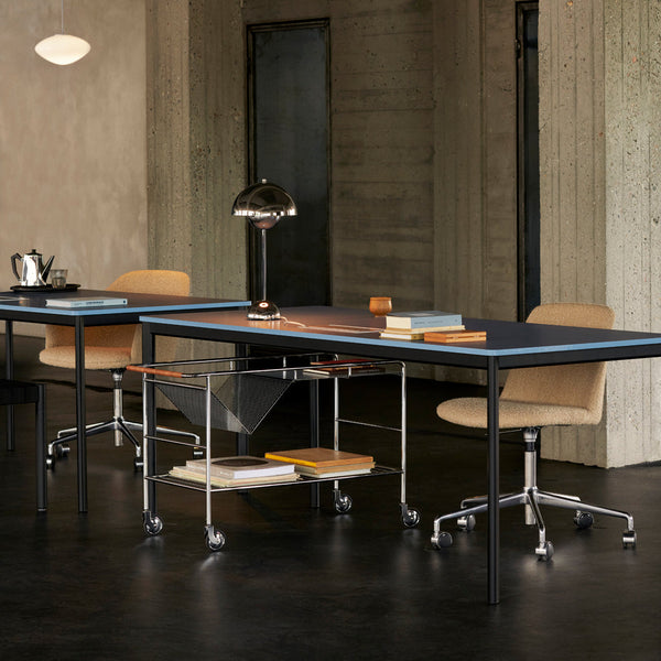 Modern office workspace featuring a sleek black desk with light wood accents and beige chairs against a concrete backdrop.
