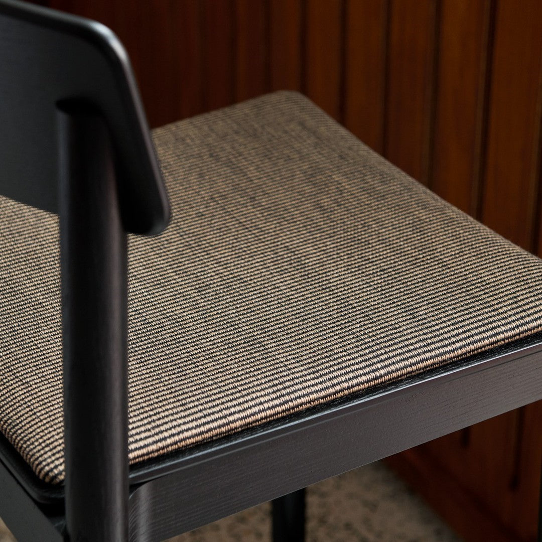 Black chair with a textured seat featuring a striped pattern in neutral tones of black and beige.
