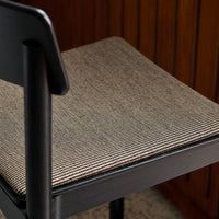 Black chair with a textured seat featuring a striped pattern in neutral tones of black and beige.