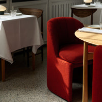 Red upholstered chair with textured pattern, paired with a wooden table and a neutral-toned floor. Cozy dining ambiance.