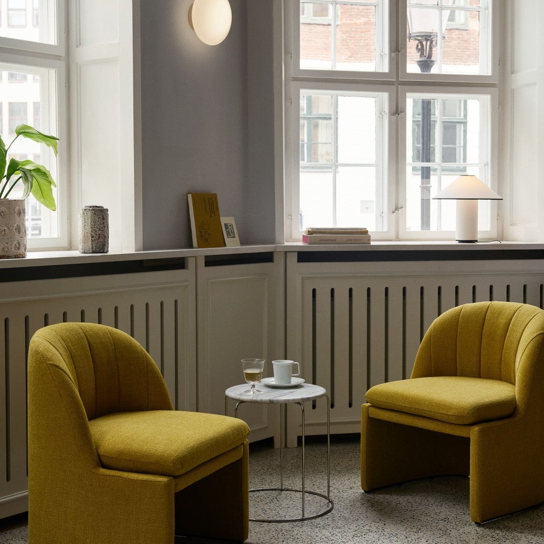 Yellow upholstered chairs with ribbed texture, set against a neutral wall and light wood accents.