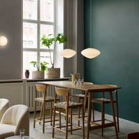 Modern dining space with earthy tones, soft grey walls, deep green accents, and warm wood textures. Elegant light fixtures.