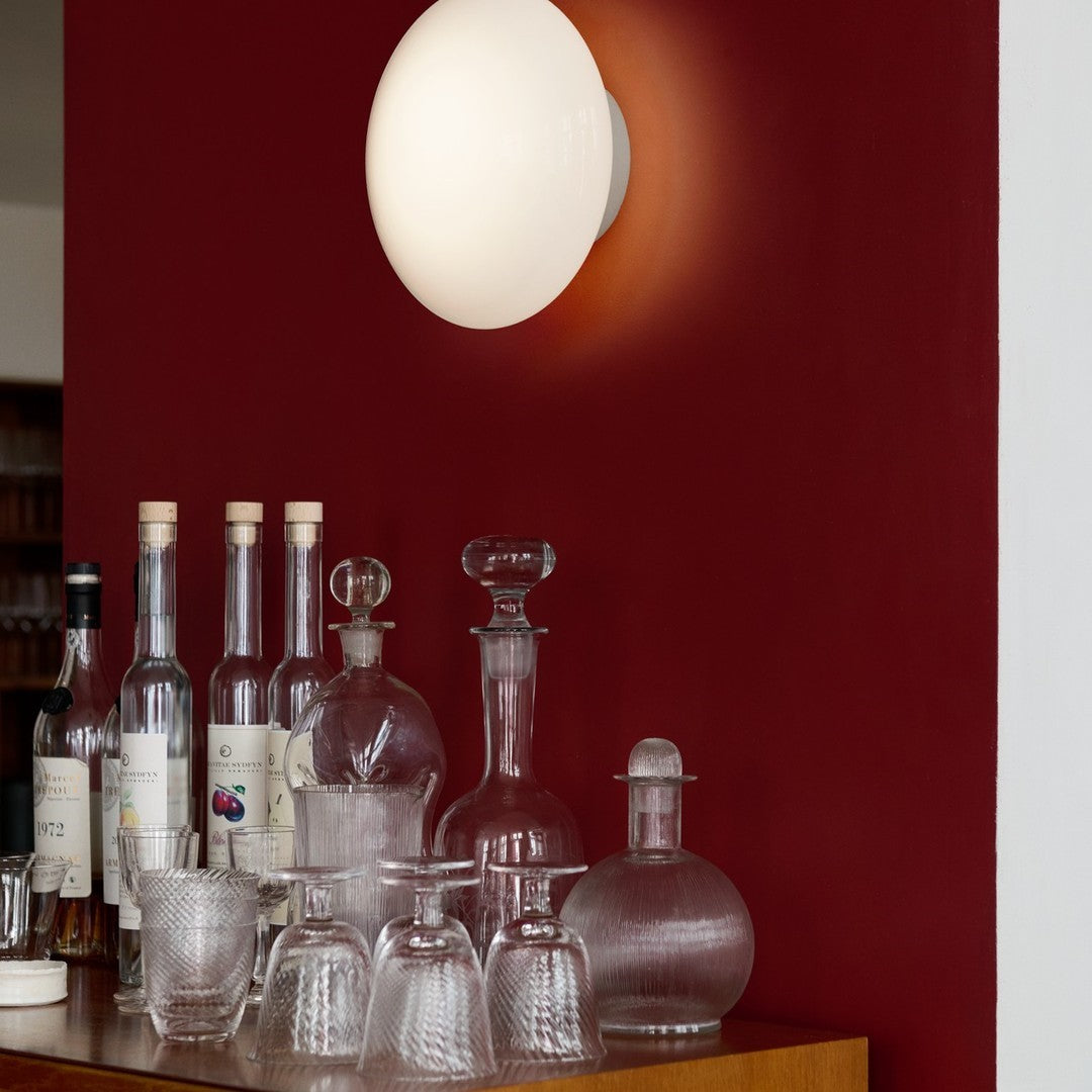 White globe wall light against a deep red wall, featuring textured glassware with clear and frosted patterns.