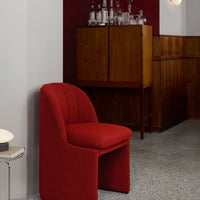 Red textured chair against a deep maroon wall, featuring subtle patterns and a stylish modern aesthetic.