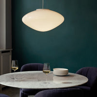 Sleek white pendant light against a deep teal wall, complemented by plush purple chairs and a marble table.