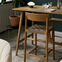 Oak wood dining set with earthy tones, featuring a checkered pattern on chairs and a subtle speckled floor design.