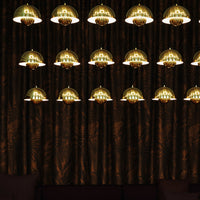 Gold pendant lights against a rich, dark patterned curtain background, creating an elegant ambiance.