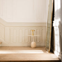 "Elegant gold and cream accent table on a light wooden floor with textured white walls."