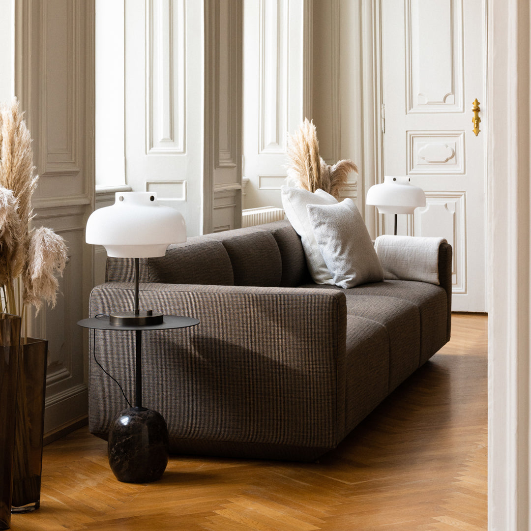 Modern grey sofa with subtle texture, complemented by light-colored decorative pillows and warm wooden flooring.