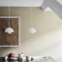 Modern white pendant lamps with soft, curved shapes against a neutral beige wall and a stylish wooden table setting.