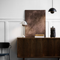 Abstract brown painting with soft gradients above a wooden sideboard, complemented by black and metallic decor elements.
