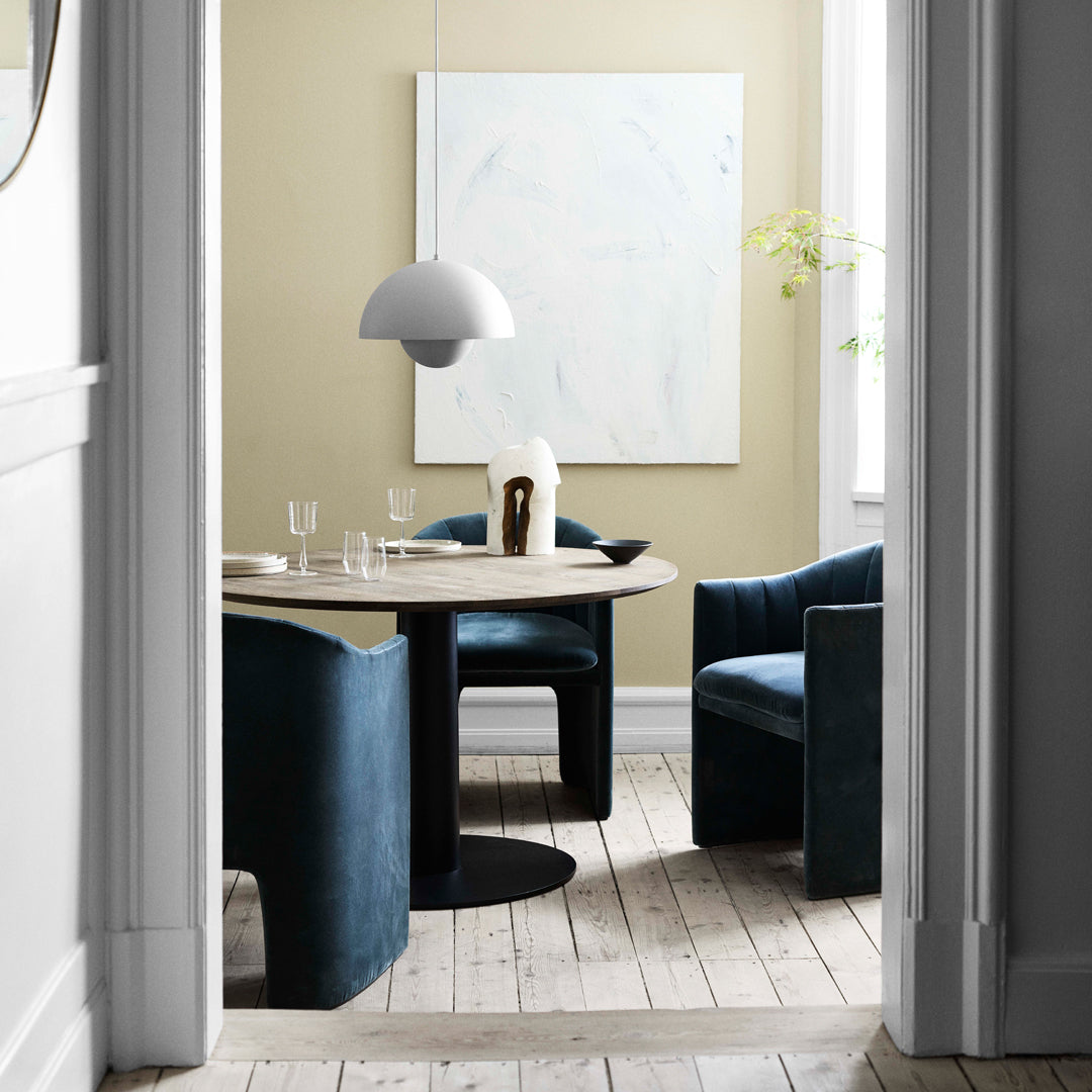 "Modern dining area with deep blue chairs, light wood table, and neutral walls featuring a minimalist artwork."