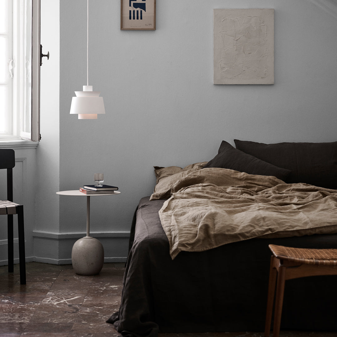 Cozy bedroom featuring neutral tones, warm beige bedding, and minimalist decor against soft gray walls.