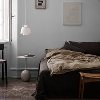 Cozy bedroom featuring neutral tones, warm beige bedding, and minimalist decor against soft gray walls.