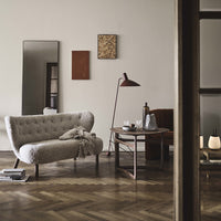 Soft beige tufted sofa, dark wooden table, and warm earthy tones in wall art create a cozy, modern living space.