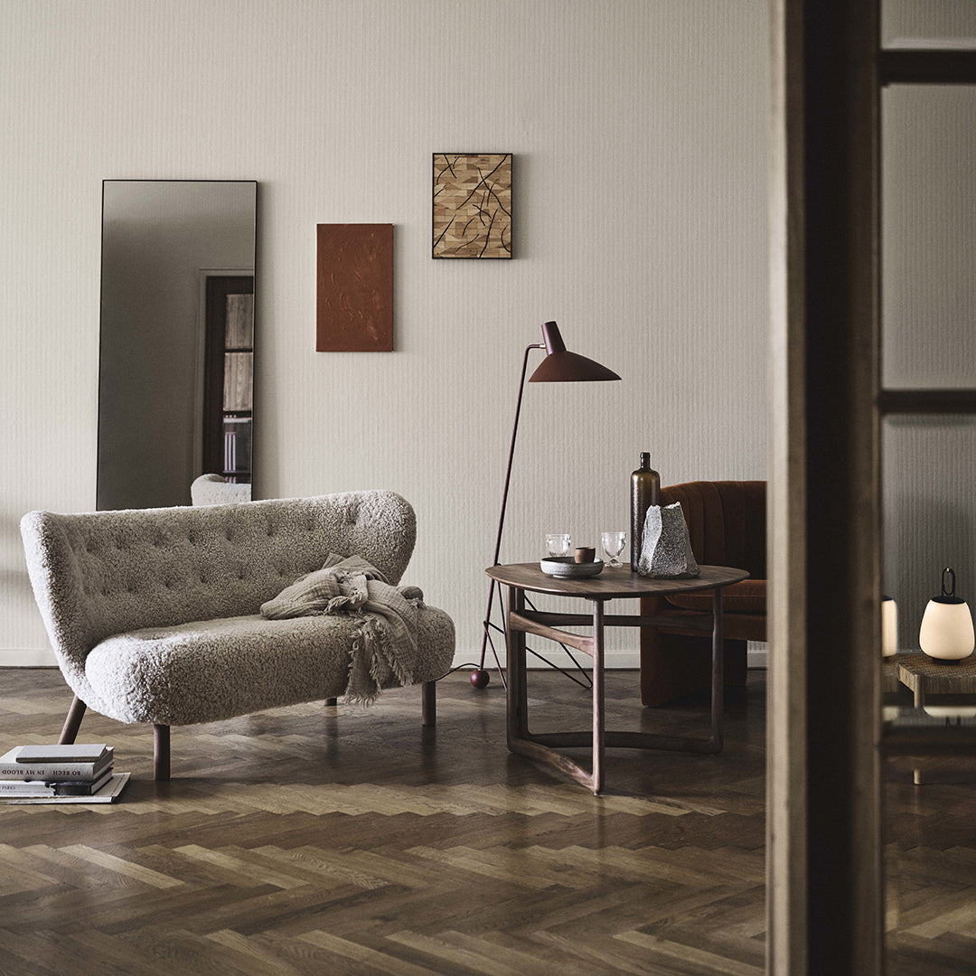 Soft beige tufted sofa, dark wooden table, and warm earthy tones in wall art create a cozy, modern living space.