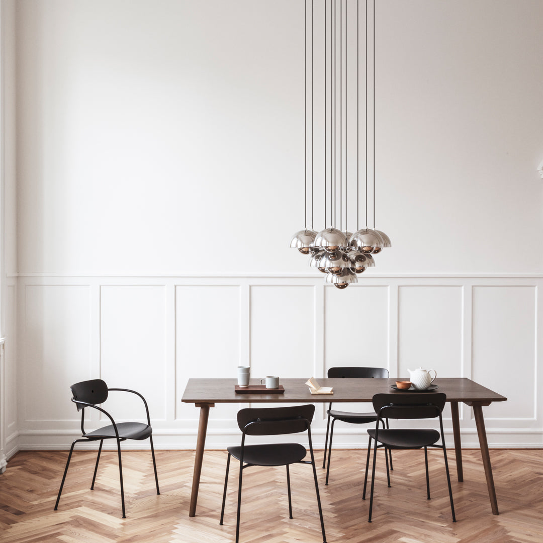 "Modern dining room featuring black chairs, wooden table, and a stylish glass pendant light against a light gray wall."