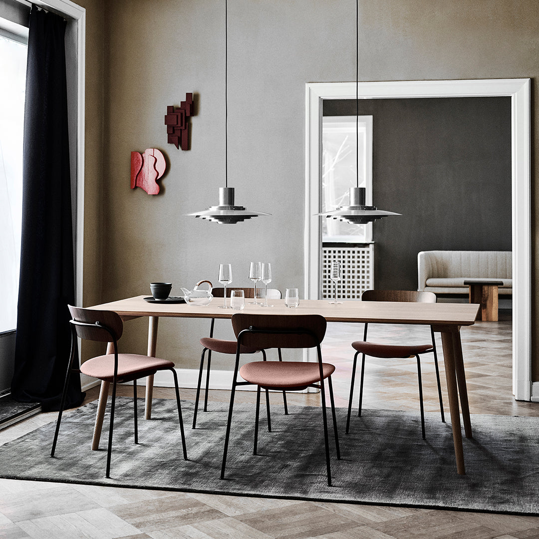 Modern dining room featuring gray walls, a light wood table, pink chairs, and a geometric patterned rug.