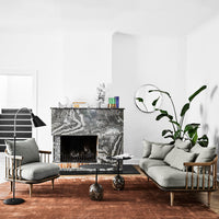 Modern living room featuring a gray sofa, black marble fireplace, and a warm rust-colored rug. Minimalist decor accents.