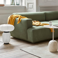 Green modern sofa with a mustard throw, paired with white and beige decor elements on wooden flooring.