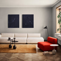 Modern living room featuring a beige couch, bold red accent chair, dark blue wall art, and warm-toned area rug.