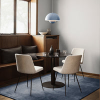 Light blue pendant lamp, neutral-toned chairs, dark table, and a soft blue rug in a cozy dining setting.