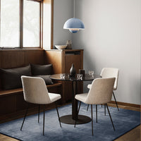 Light blue pendant lamp, neutral-toned chairs, dark table, and a soft blue rug in a cozy dining setting.