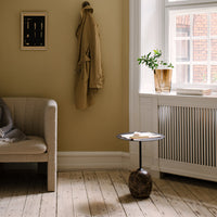 Neutral beige walls, textured cream sofa, natural wood flooring, and a dark ceramic table with a white top.