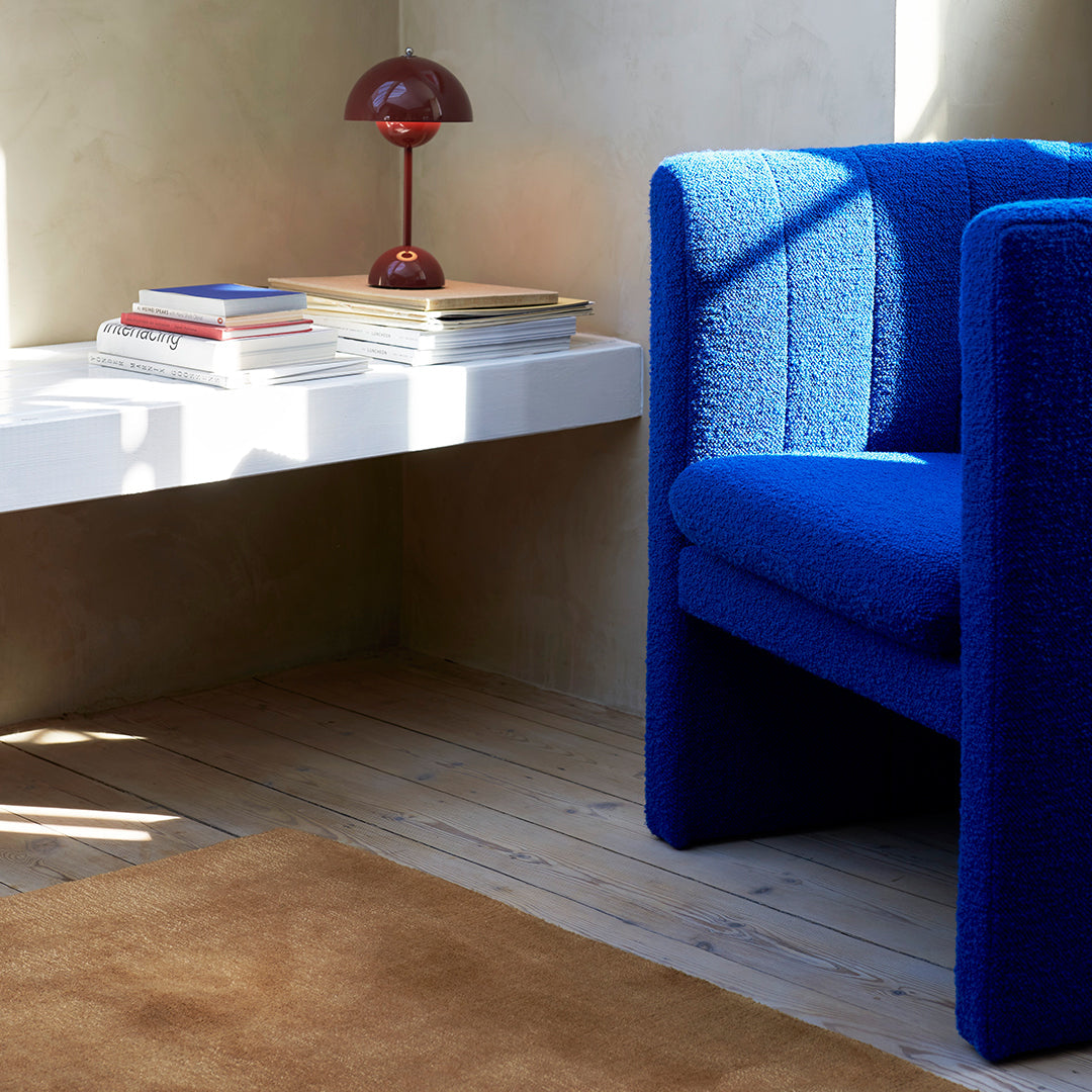 Vibrant blue textured chair next to a white table and warm brown rug, enhancing modern decor aesthetics.