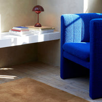 Vibrant blue textured chair next to a white table and warm brown rug, enhancing modern decor aesthetics.