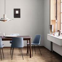 "Modern dining room featuring gray walls, light wood flooring, and blue chairs in a minimalist design."