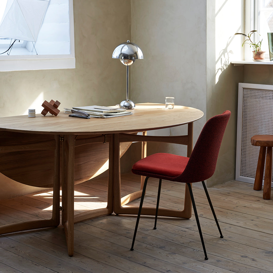 Modern wooden desk with curved lines, red upholstered chair, and natural earthy tones. Elegant simplicity and warmth.
