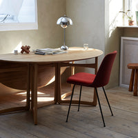 Red upholstered chair with black legs, light wood table, and neutral-toned walls create a modern, warm atmosphere.