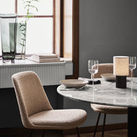 Beige textured chair with a marble table, clear glass vase, muted gray walls, and warm lighting for a cozy ambiance.