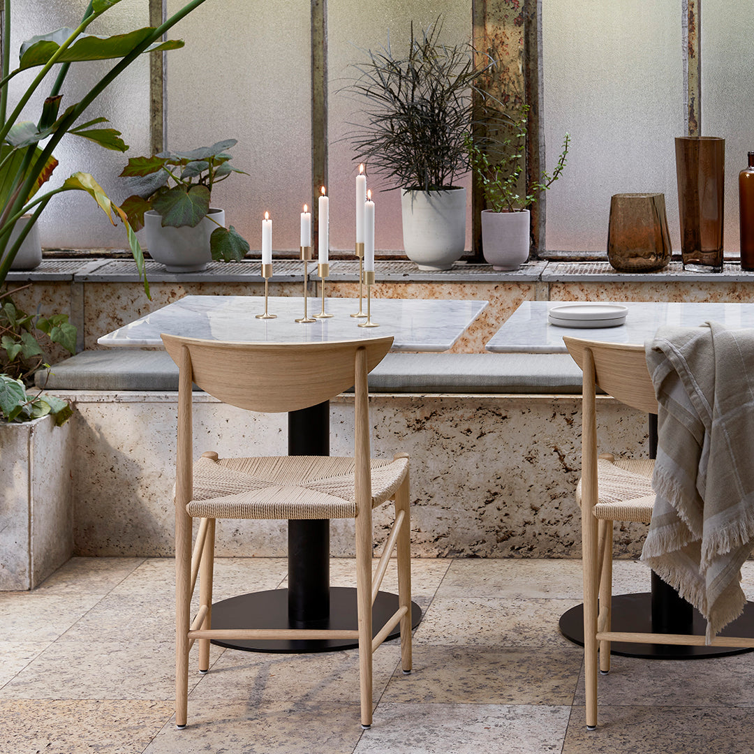 Natural wood tones and soft beige chair patterns, contrasted with sleek black table and earthy stone textures.