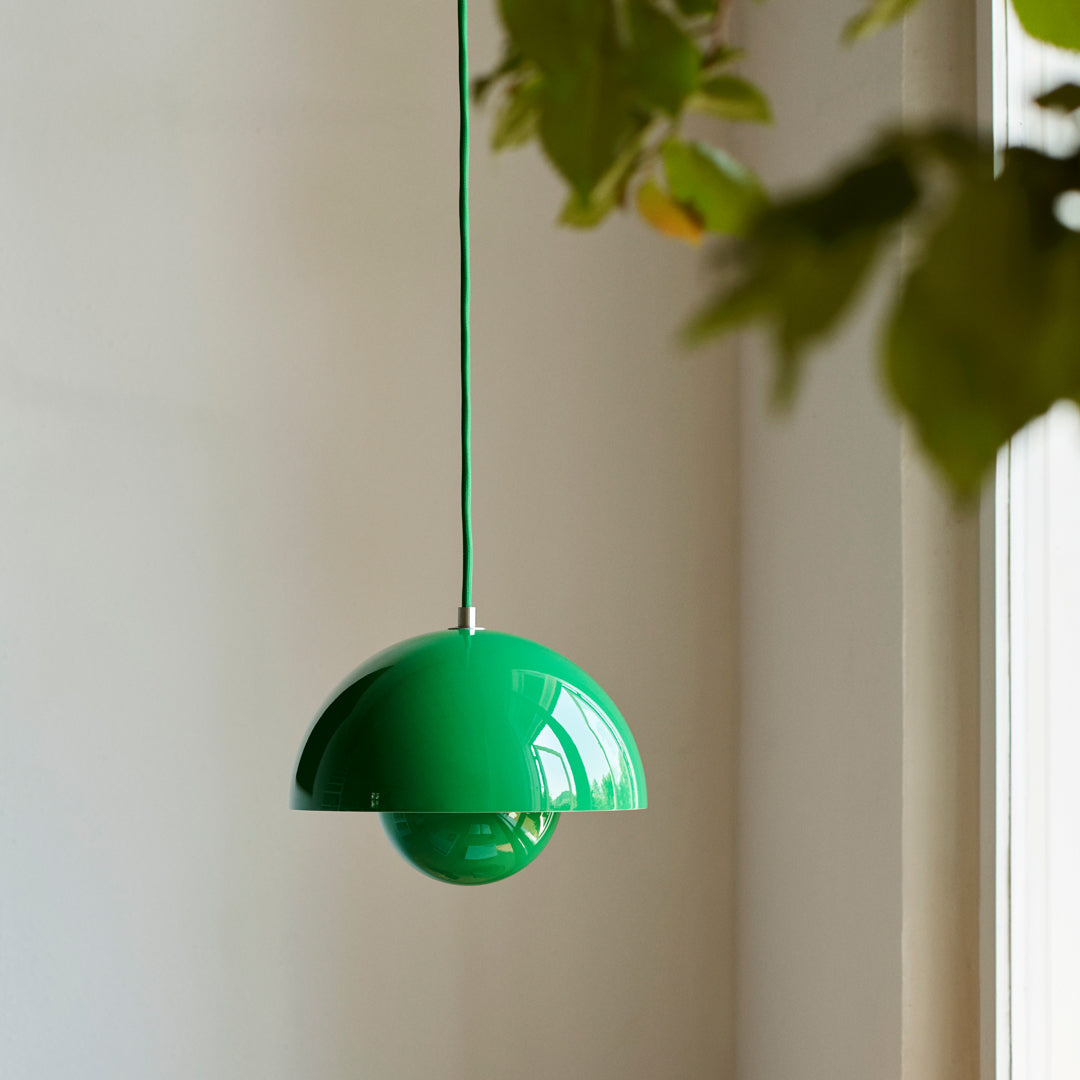 Glossy green pendant lamp with a sleek, modern design, featuring a round shade and a matching green cord.