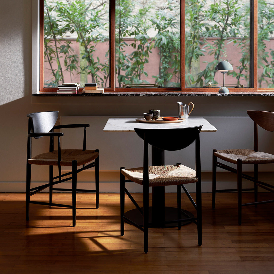Modern dining table with a white marble top, paired with black and natural wood chairs, featuring a minimalist design.