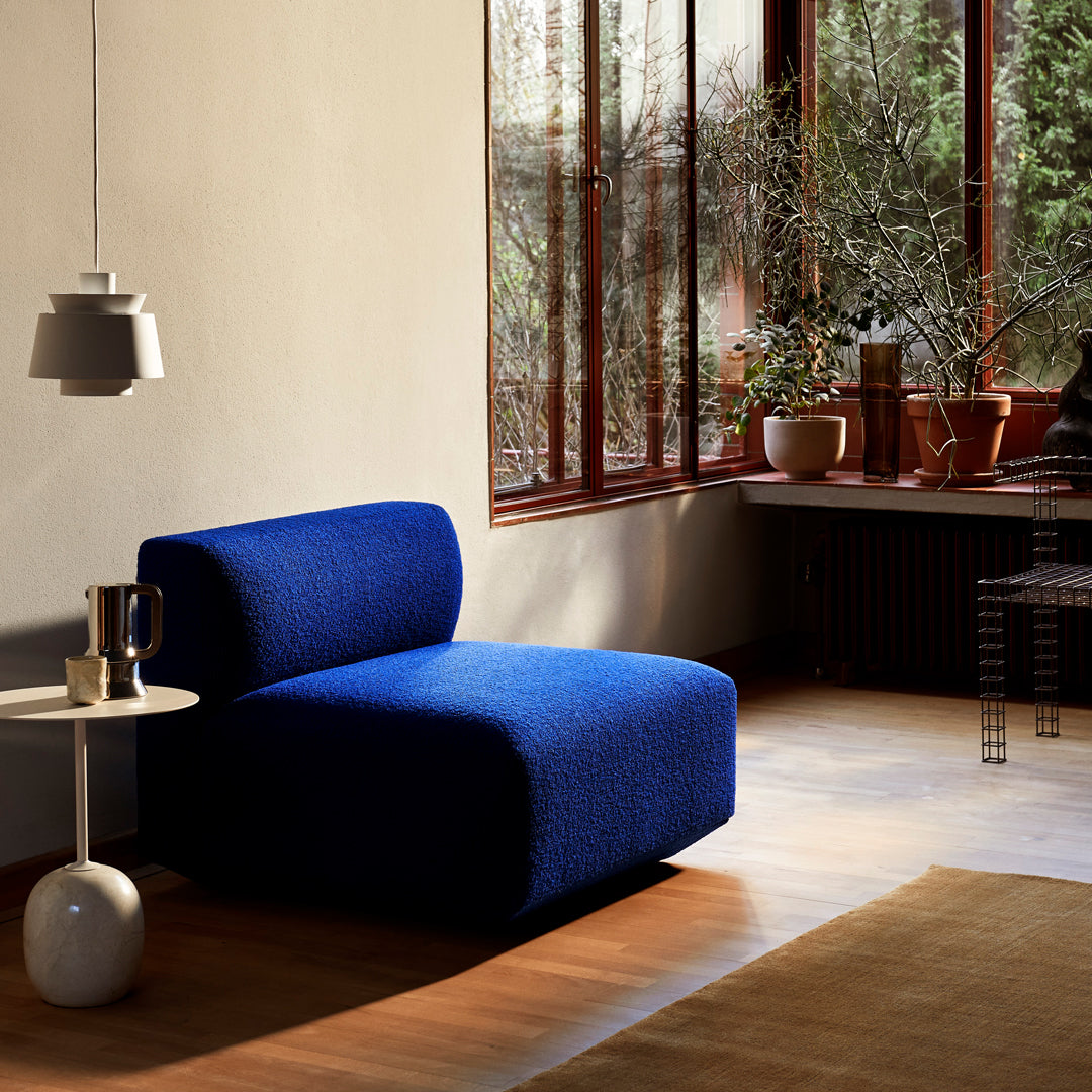 Vibrant blue upholstered chair in a modern setting, featuring a textured fabric and minimalist design.