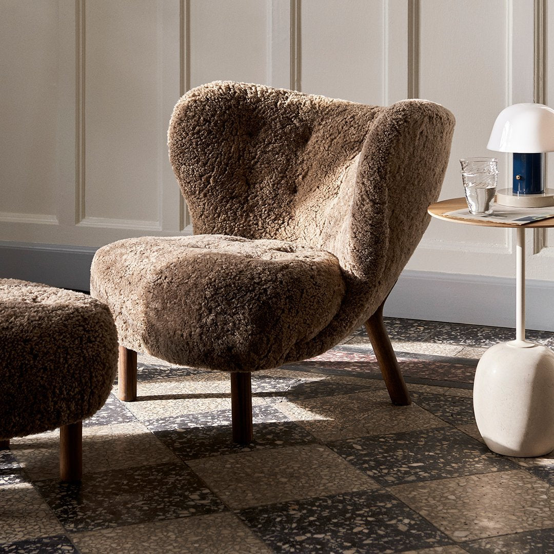 Cozy brown plush chair with a unique curved silhouette, set against a patterned floor.
