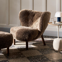 Cozy brown plush chair with a unique curved silhouette, set against a patterned floor.