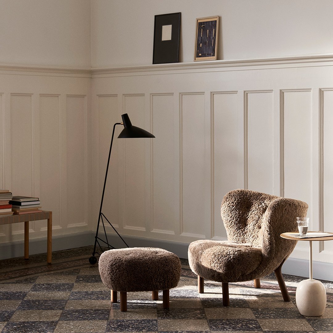 "Cozy brown accent chair and ottoman with a textured, plush pattern against a neutral-toned wall and patterned floor."