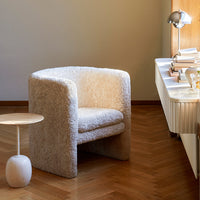 Cozy ivory boucle armchair with soft texture, paired with a minimalist round side table in a stylish indoor setting.
