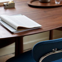 Blue upholstered chair beside a sleek wooden desk, with light gray and white papers on the surface, creating a modern aesthetic.