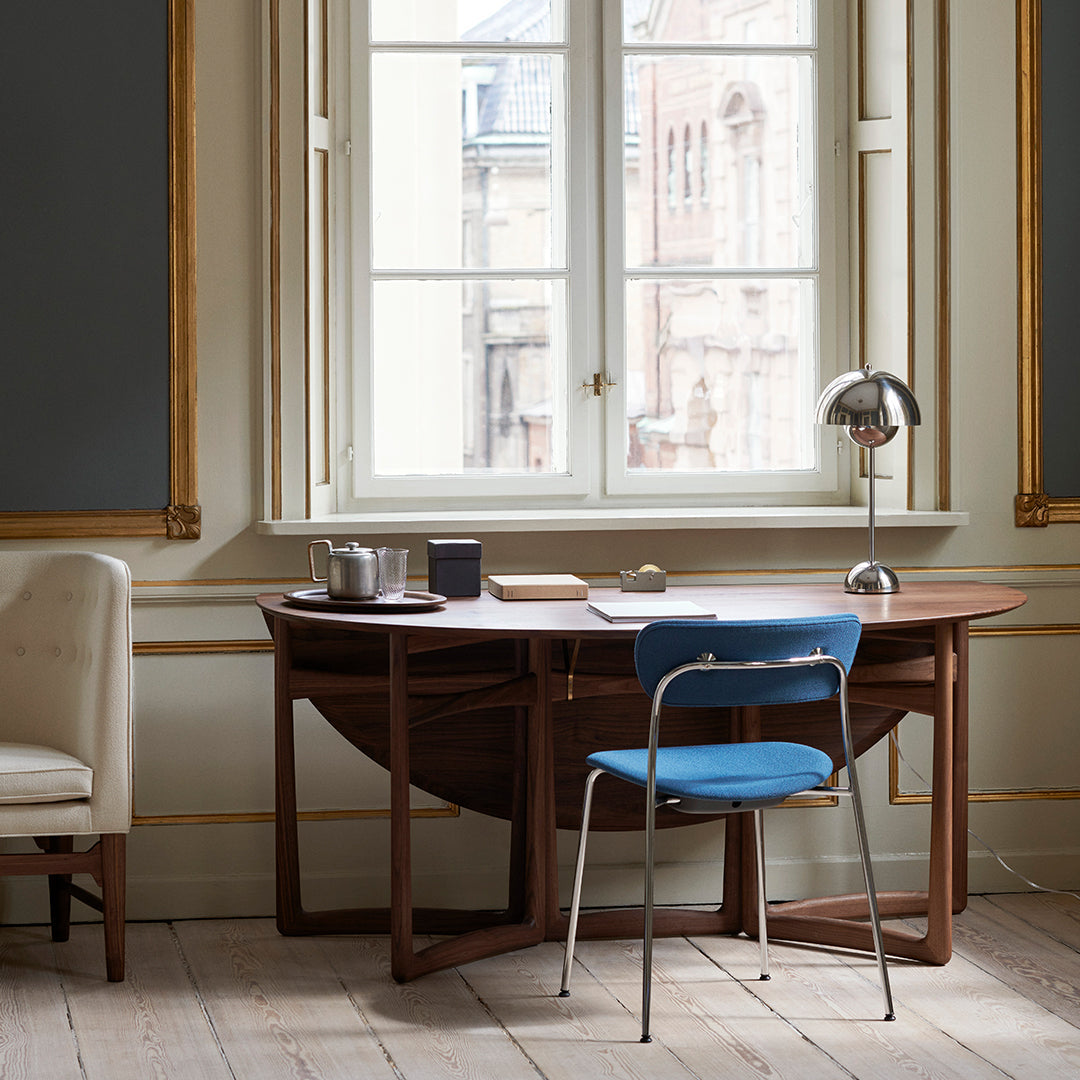 Modern wooden desk with rich brown tones, paired with a vibrant blue chair against a light beige backdrop.
