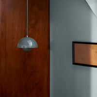 Gray pendant light with a sleek design against rich wood and muted blue wall. Modern Scandinavian pattern accents.