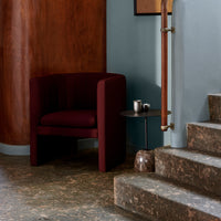 Burgundy accent chair against a blue wall, paired with a marble-patterned floor and smooth wooden accents.
