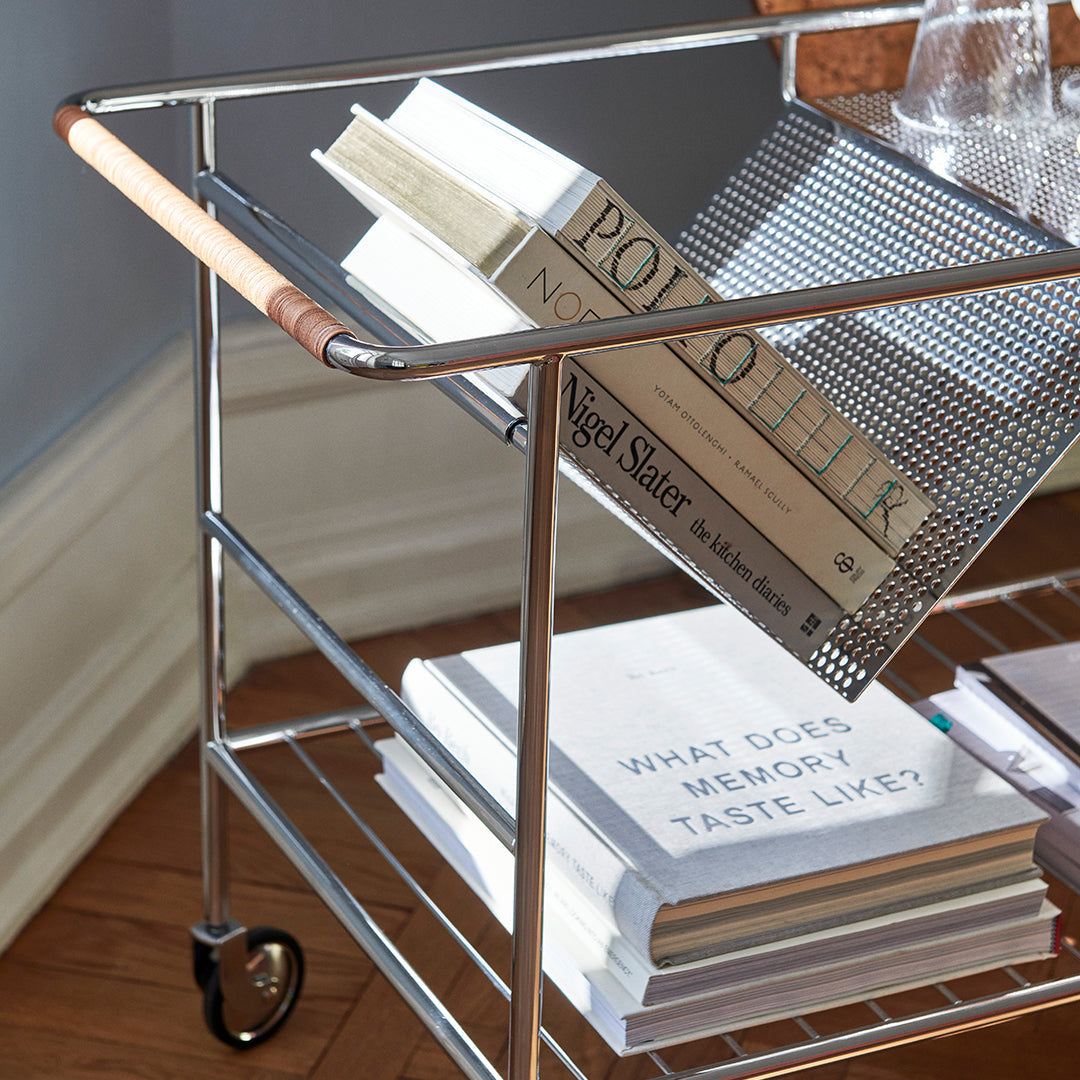 Chrome bar cart with a mix of matte and glossy textures; features wood accents and layered white book covers.
