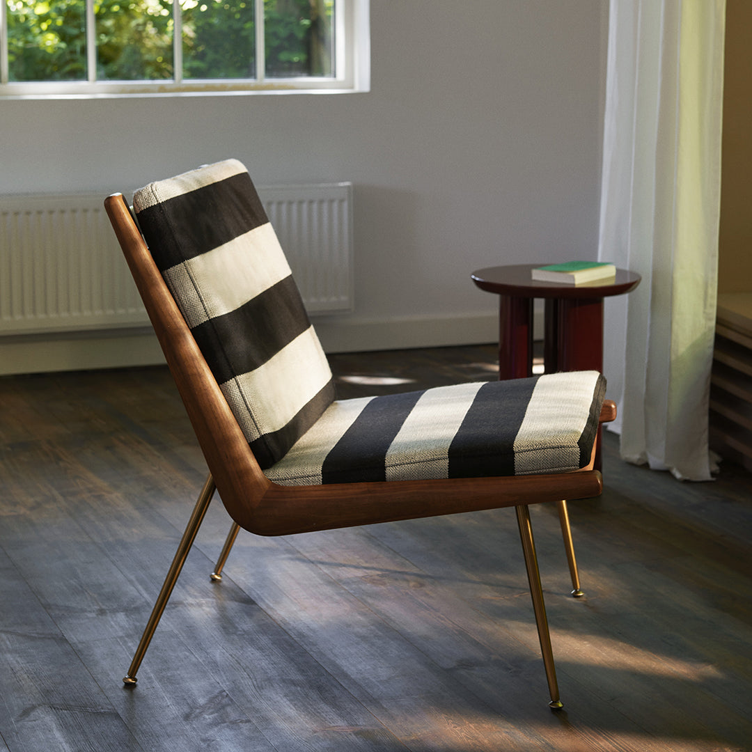 Black and white striped seat cushion on a modern chair with a wooden frame and gold legs.