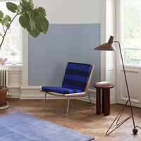 Blue striped chair with a light blue wall and a soft blue rug in a bright, airy room.
