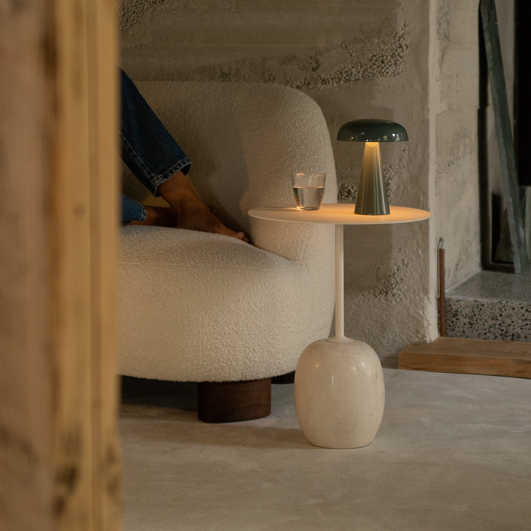 "Modern lamp with a green shade and white base, paired with a cozy cream sofa in a neutral-toned room."